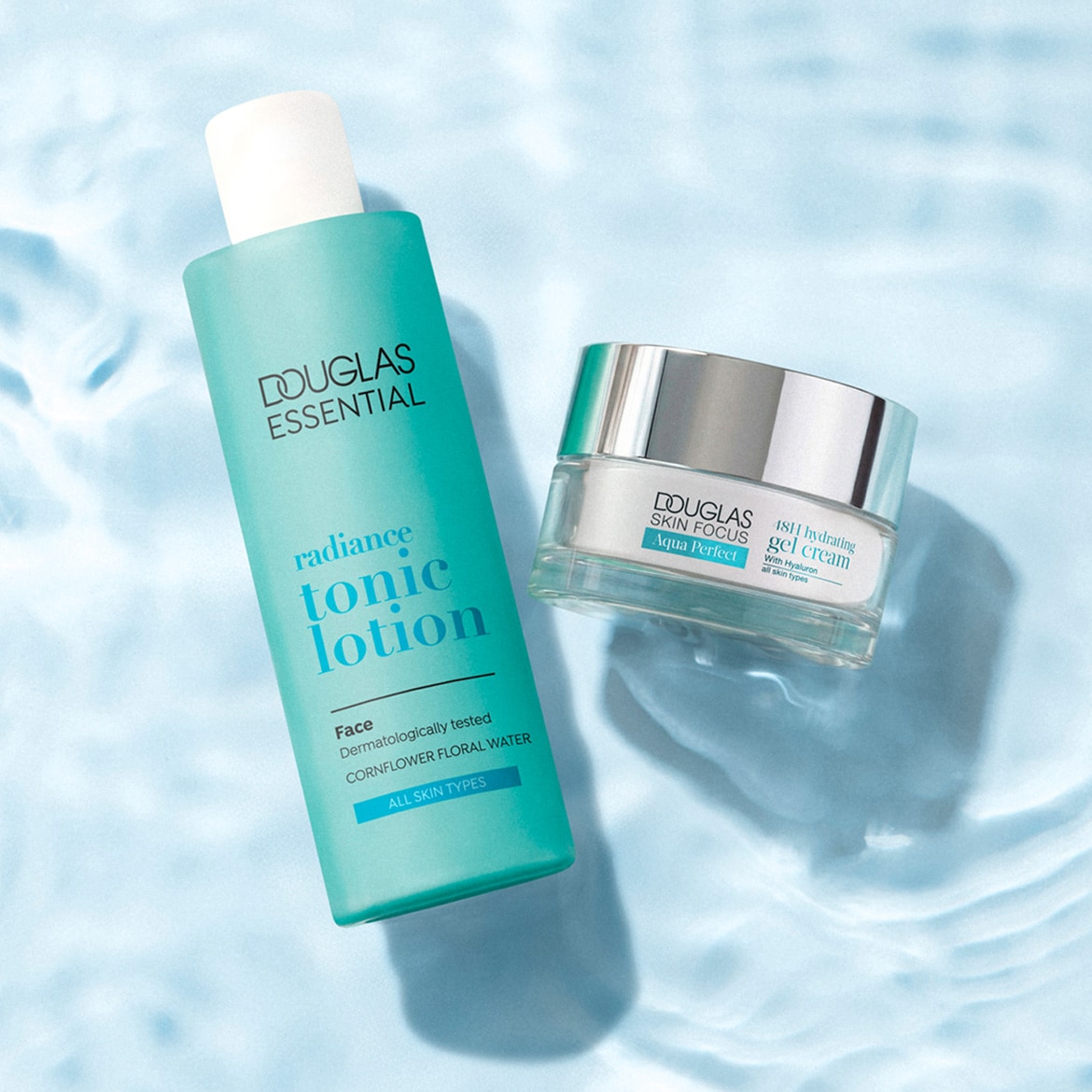 De Douglas Essential Radiance Tonic Lotion en Douglas Skin Focus Aqua Perfect 18H Hydrating Gel Cream, beide in blauwgroene verpakkingen, staan op een lichtblauwe ondergrond met waterrimpelingen.