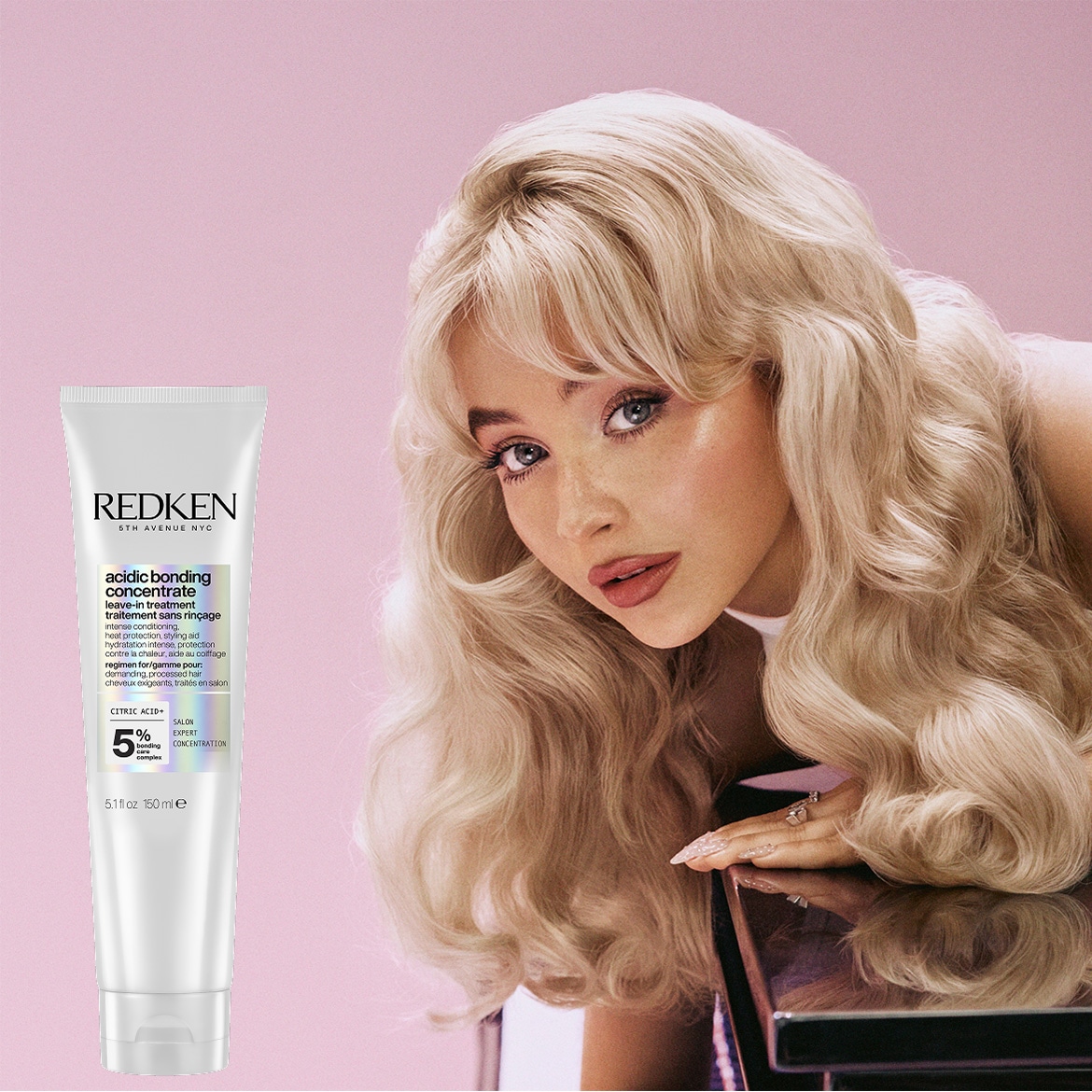 Blonde vrouw poseert naast een witte tube Redken Acidic Bonding Concentrate leave-in treatment, die intense hydratatie, hittebescherming en stylinghulp biedt voor veeleisend, behandeld haar.