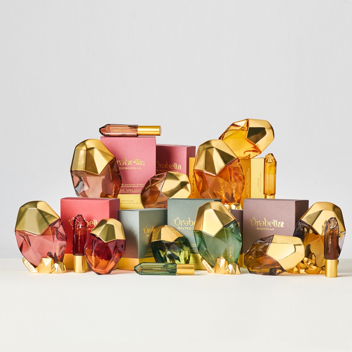 Ontdek de luxe van Òrabella parfums, gepresenteerd in flessen met gouden accenten en kleurrijke dozen, klaar om je zintuigen te prikkelen.