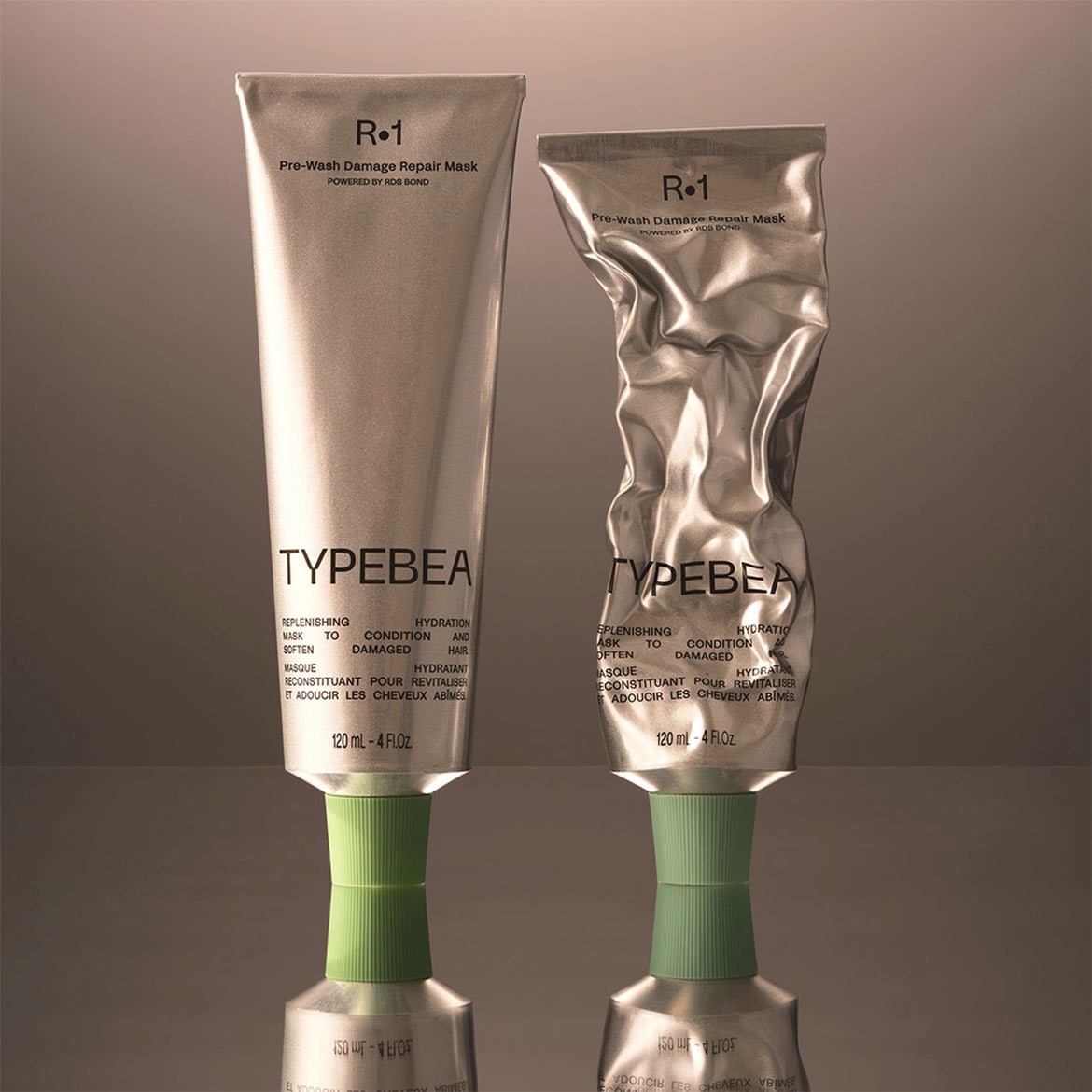 Twee zilverkleurige tubes Typebea R-1 Pre-Wash Damage Repair Mask, waarvan één vol en één ingedeukt, beloven hydratatie en herstel voor beschadigd haar.
