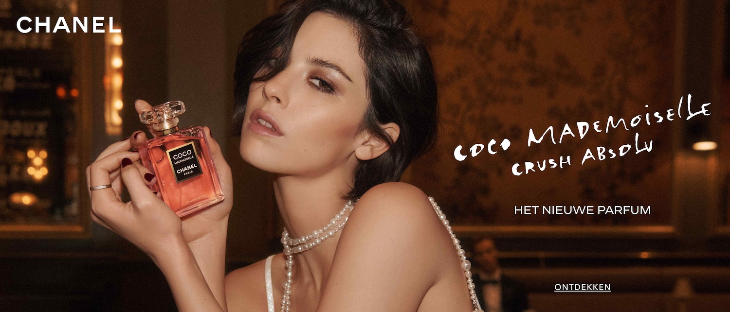 Ontdek Coco Mademoiselle Crush Absolu, het nieuwe parfum van Chanel, gepresenteerd door een vrouw met een parelketting die de roze parfumfles vasthoudt.