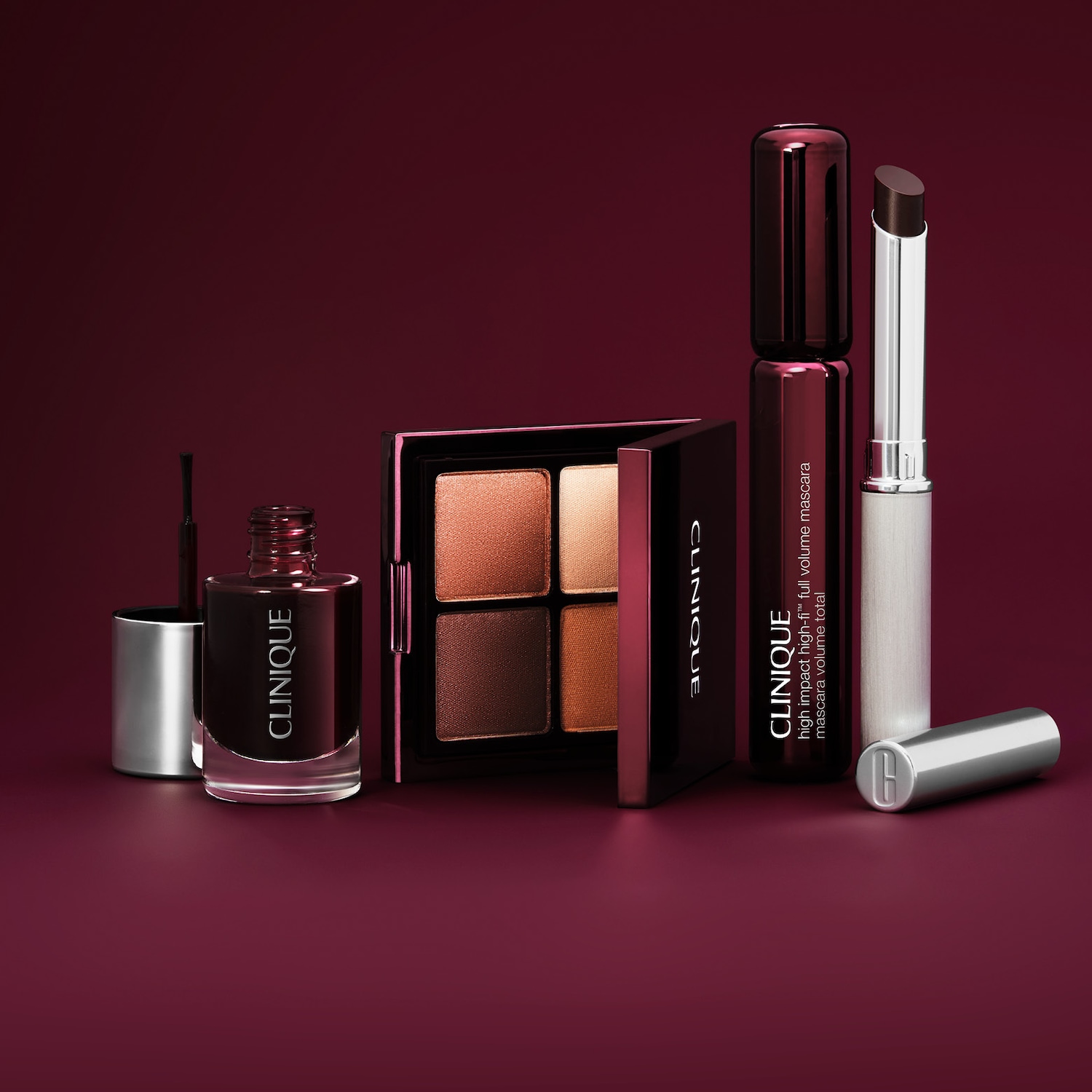 Een Clinique nagellak in een donkerrode tint, een oogschaduwpalet met vier aardetinten, een Clinique High Impact High-Fi Full Volume Mascara en een lippenstift in een donkerbruine tint, allemaal op een donkerrode achtergrond.