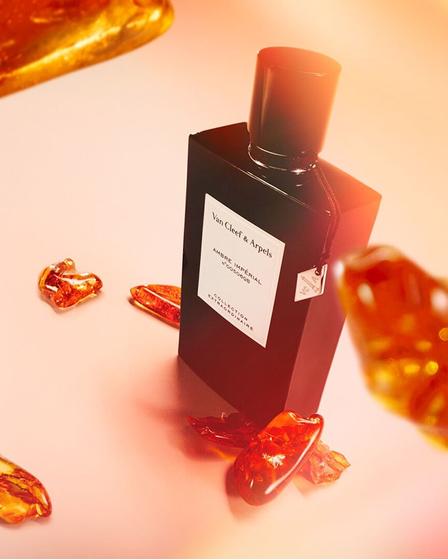 Ontdek Van Cleef & Arpels Ambre Impérial, gepresenteerd in een elegante zwarte flacon, omringd door amberkleurige accenten.