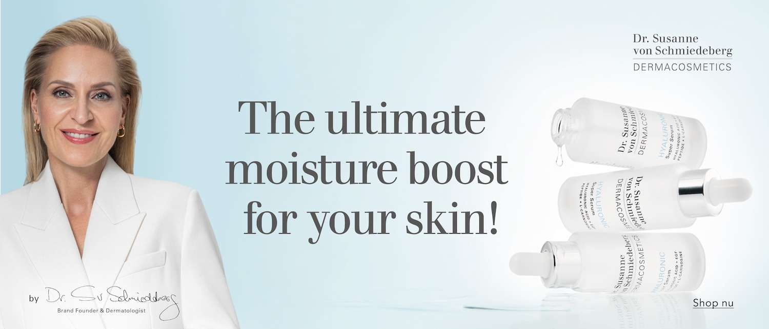 Dr. Susanne von Schmiedeberg, een blonde vrouw met een witte blazer, glimlacht en presenteert haar dermacosmetica, waaronder drie flacons Hyaluronic Super Serum, voor de ultieme vochtboost voor je huid. Shop nu.