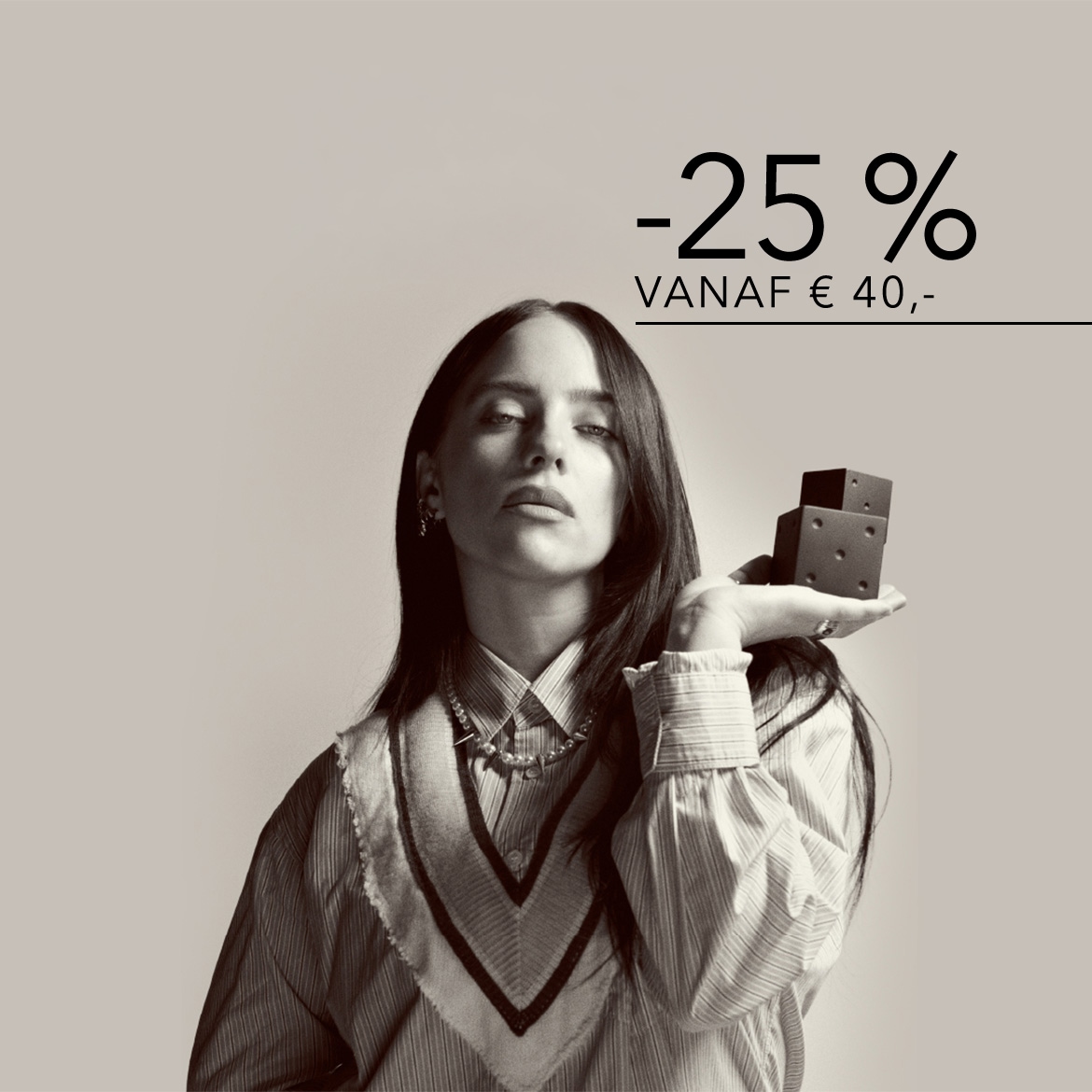 Een zwart-witfoto van Billie Eilish die twee zwarte dobbelstenen in haar hand houdt, met de tekst "-25% VANAF € 40,-" in de rechterbovenhoek.