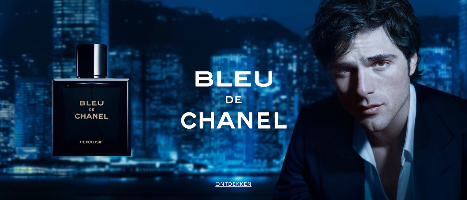 Bleu de Chanel L'Exclusif, gepresenteerd in een strakke, donkerblauwe flacon, straalt tijdloze elegantie uit tegen een achtergrond van een nachtelijk stadsgezicht en een zelfverzekerde man.