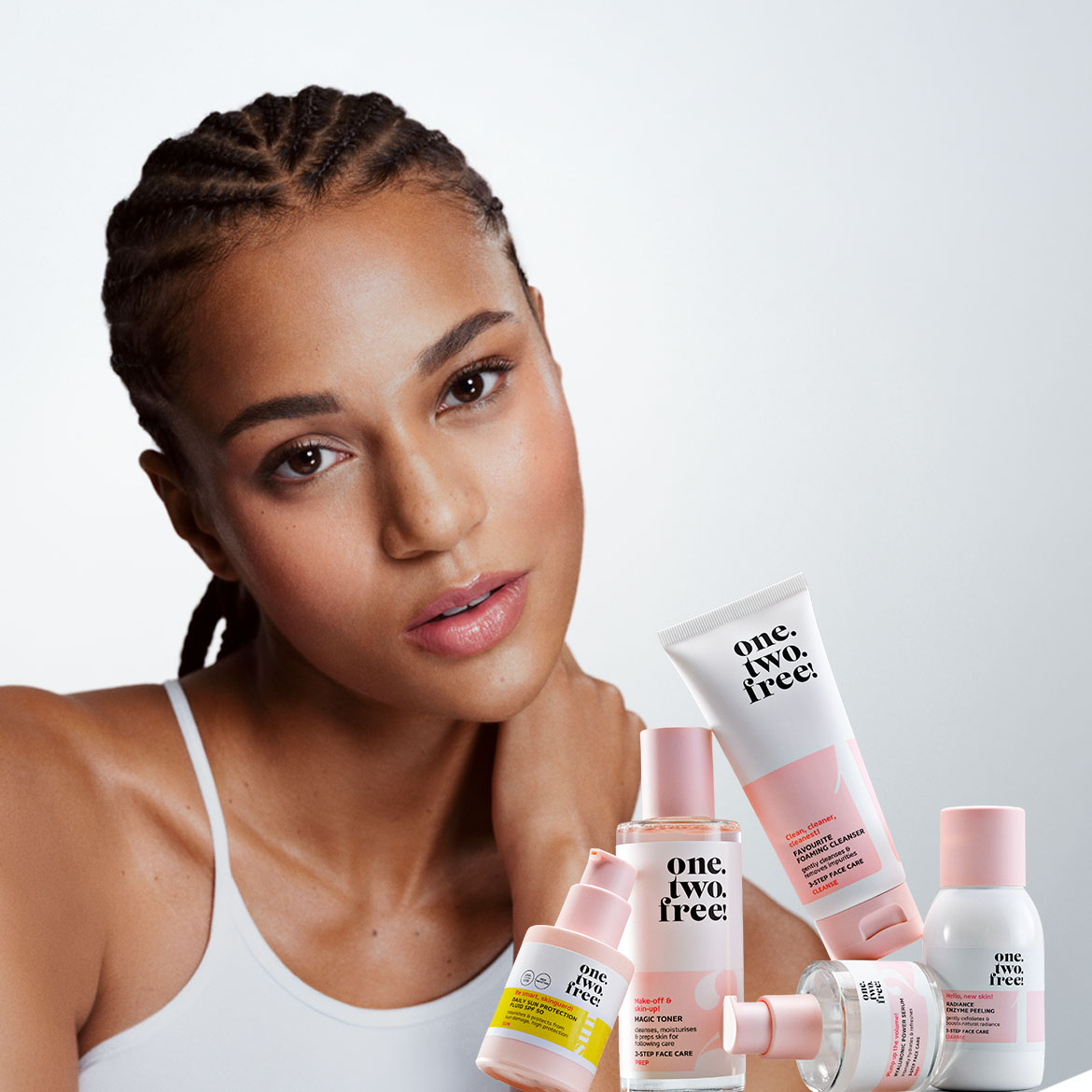 Ontdek de "one. two. free!" huidverzorgingslijn met witte verpakkingen en roze accenten, inclusief reiniger, toner en serum, voor een complete 3-staps gezichtsverzorging.