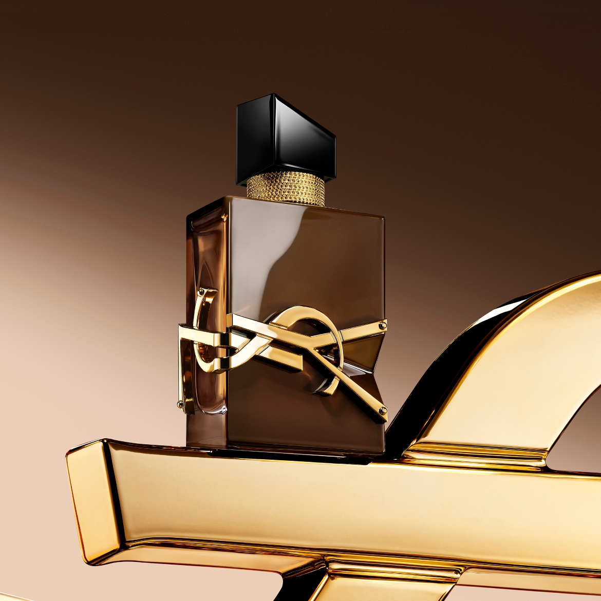 De Libre Le Parfum van Yves Saint Laurent is een amberkleurig parfum in een bruine, vierkante fles met een gouden YSL-logo en een zwarte dop, staand op een glanzend gouden oppervlak.